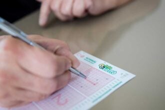 ötöslottó egy férfi tollal szerencsejátékot játszik, megtippeli a számokat