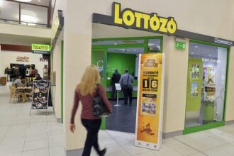 lottó egy nő megy el az üzlet előtt, többen szerencsejátékot játszanak odabent