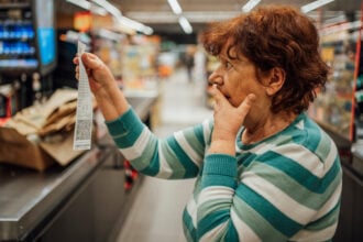 vásárlás idős nő nézi a számlát a kasszánál és kétségbe van esve