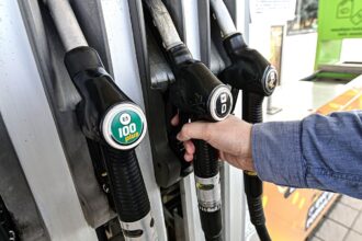 benzinkút ember tankol töltőpisztolyok a képen pulóverben van az autós