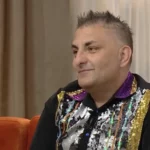 Gáspár Győző színes fekete ruhában egy narancssárga kanapén ül a tv2 mokka reggeli műsorában