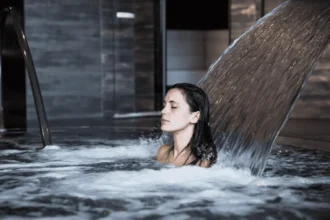 Nő a vízsugár alatt a termálfürdő medencéjében