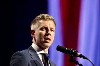 Magyar Péter zakóban mikrofon előtt beszél