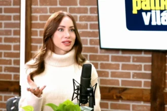 Kiara Lord a tenyerét felfelé tartva gesztikulál egy fehér, galléros pulcsiban a Palikék világa elnevezésű YouTube-csatorna műsorában.