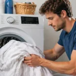 Egy fiatal férfi lepedőket szed ki az elöltöltős mosógép dobjából.