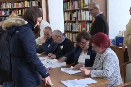 Egy választópolgár szavaz Egerben, miközben a választási bizottság tagjai ellenőrzik az okmányai érvényességét.